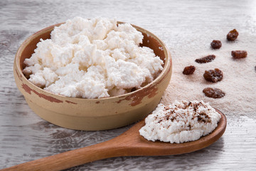 Cottage cheese with raisins in the dish on the wooden table in the kitchen. Tasty, sweet meal. Healthy eating and lifestyle.