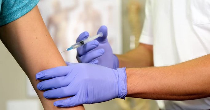 Male therapist injecting female patient in clinic 4k