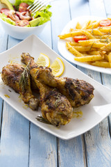 Grilled chicken legs fried tomatoes vegetables fresh salad avocado spices food in the kitchen
