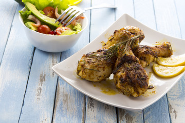 Grilled chicken legs fried tomatoes vegetables fresh salad avocado spices food in the kitchen
