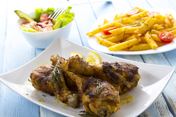 Grilled chicken legs fried tomatoes vegetables fresh salad avocado spices food in the kitchen
