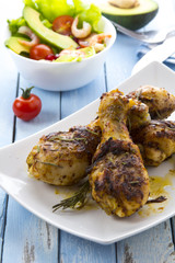 Grilled chicken legs fried tomatoes vegetables fresh salad avocado spices food in the kitchen
