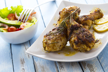 Grilled chicken legs fried tomatoes vegetables fresh salad avocado spices food in the kitchen
