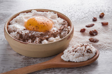Recipe ingredients for cake. Cottage cheese, egg, semolina, raisins and cinnamon on the wooden table in the kitchen. Tasty, sweet meal. Healthy eating and lifestyle.