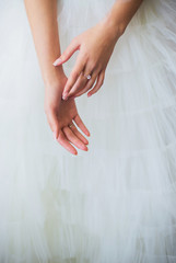 Beautiful aristocratic thin girl's hand on a background of white fluffy skirt. Graceful ballerina in white tutu. touch fingers with tenderness and ease.