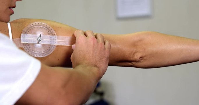 Male therapist measuring female patient's back with medical ruler	Male therapist measuring female patient's back with medical ruler in clinic 4k