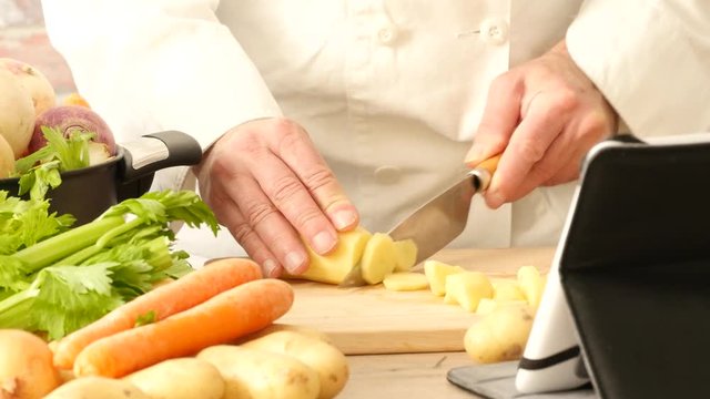 detail of hands of a chef slicing potatoes