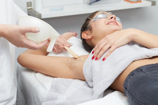 Young woman having underarm laser hair removal treatment in salon