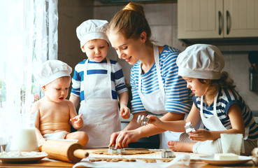 happy family in kitchen. mother and children preparing dough, ba