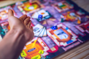 Hand throws the dice on the background of Board games