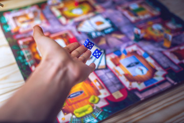 Hand throws the dice on the background of Board games