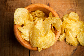 Patatas fritas dentro de un cuenco de madera sobre tabla de madera rústica. Vista de superior
