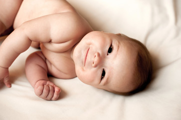 Soft picture of a beautiful baby boy laying on white bedding