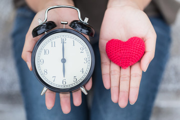 give time with love, showing retro clock and red heart on hand. - obrazy, fototapety, plakaty