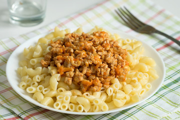 Macaroni with meat on a white plate