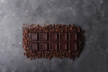 Chocolate and coffee beans .Dark chocolate background. A large bar of chocolate on gray abstract background. Background with chocolate. Sweet food photo concept. Copyspace