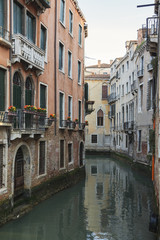 Fototapeta na wymiar Vintage Venetian facades with small balconies reflects in canal