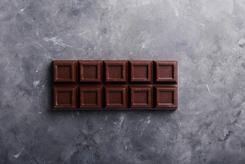 A large bar of chocolate on gray abstract background. Background with chocolate. Chocolate. Sweets