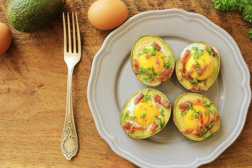 Avocado Egg Boats with bacon on wooden table. Top view.