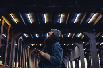 Obraz premium Woman in hat holding mobile phone and looking up
