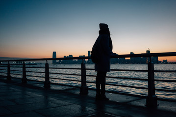 Fototapeta premium Silhouette of woman standing at the railing on a seafront