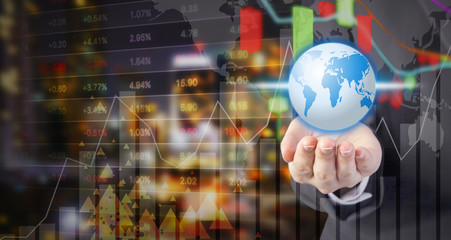 Business woman hand holding world with stock market design at night city view
