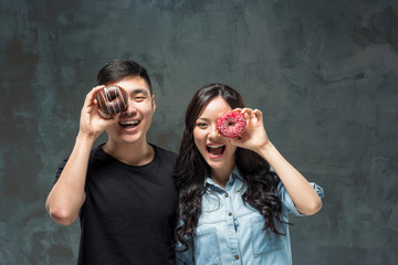 Young asian couple enjoy eating of sweet colorful donut
