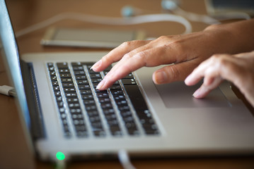 Fototapeta na wymiar Woman hands type text on notebook keyboard in a dark room