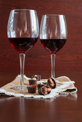 Two glasses of wine on a wooden table.  Candies.