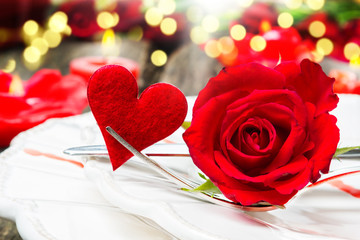 Valentinstag, Gedeck mit Rose und Herz vor Kerzenlicht