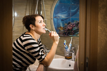 Pretty girl cleans teeth in a bathroom