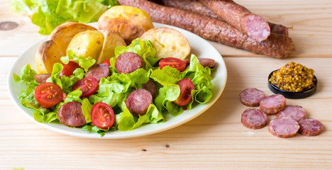 Smoked sausage with vegetables salad on a wooden board