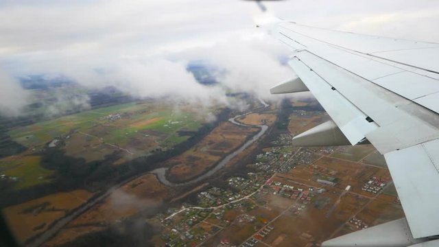 Airplane preparing to land, flying through clouds, aerial shot
