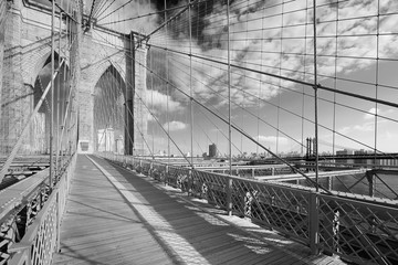Fototapeta premium Empty Brooklyn Bridge footpath in a sunny day, New York in black and white