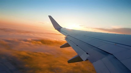 Plane flight above the clouds, sun glimpse over wing
 - Powered by Adobe