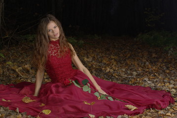 Fototapeta premium Girl in a red dress with a rose in her hand
