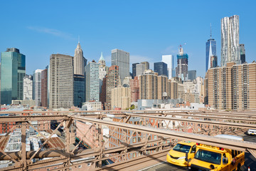 New York city skyline from Brooklyn Bridge, yellow taxi passing