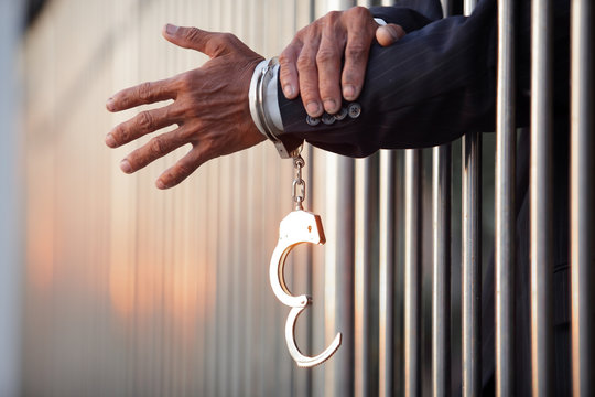 hand of businessman locked with handcuff in jail with copyspace