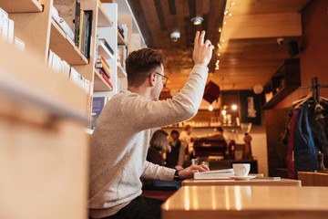 Handsome man sitting in cafe while call the waiter.