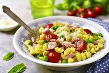 Pasta with vegetables and ham in a vintage bowl.