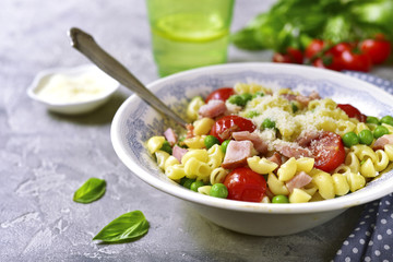 Pasta with vegetables and ham in a vintage bowl .