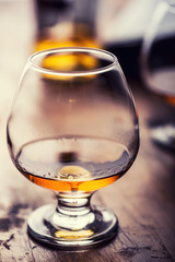 Glass whiskey cognac brandy or rum.One half full glasses of cognac on a wooden surface.
