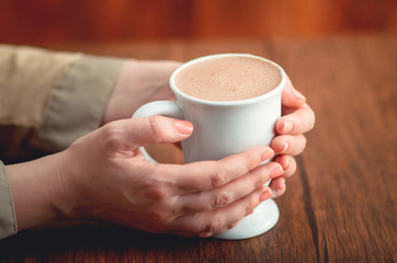 Female hands  holding hot cup of cacao
