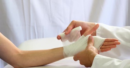 Physiotherapist putting bandage on injured hand of patient in clinic 4k - Powered by Adobe