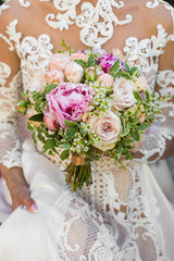 Gorgeous wedding bouquet made of peonies and roses and held by b