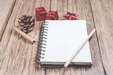 white blank space notebook with pencil and christmas ornament on wooden table