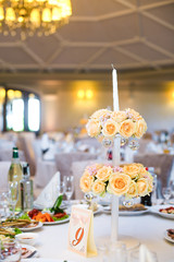 Beige roses decorate white candleholder