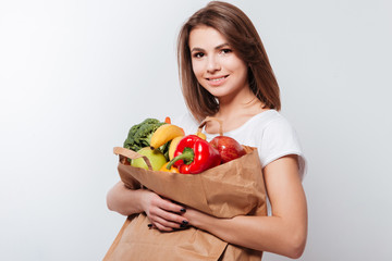 Cheerful young lady holding fruits and vegetables