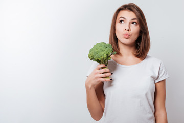 Thoughtful young lady holding broccoli
