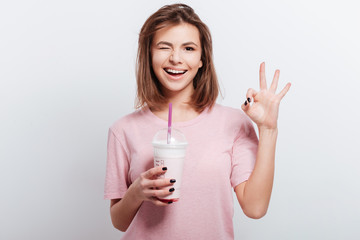 Woman holding cocktail in hands and make okay gesture.